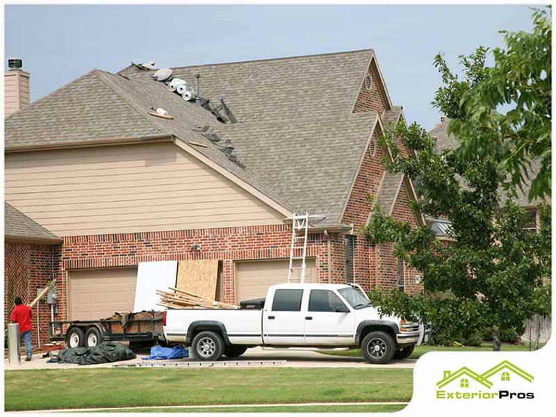 White pickup truck in front a home that just had new shingles installed by workers